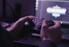 Mains crispées sur une manette de jeu devant un écran affichant une notification suspecte dans une pièce sombre