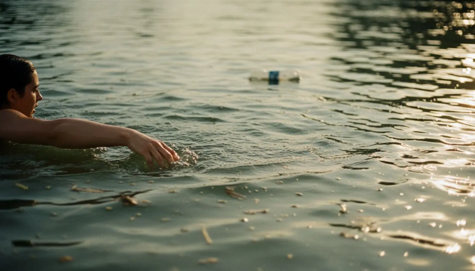 Bras d'un nageur entrant dans les eaux verdâtres de la Seine sous une lumière naturelle d'été